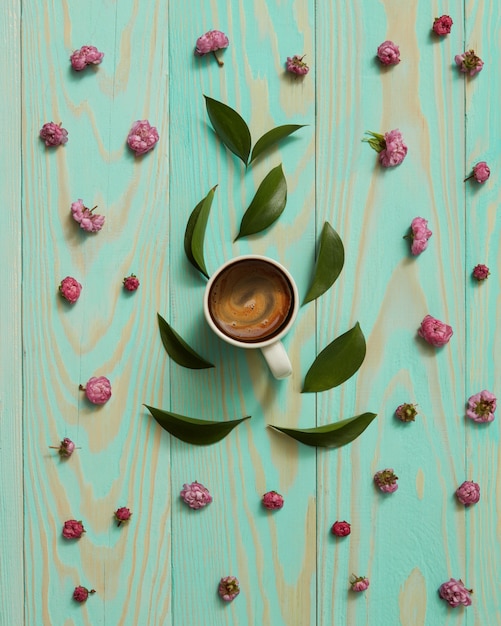 Taza de café negro decorado con flores rosas y hojas planas