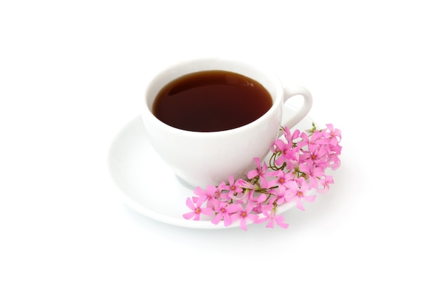 Una taza de café negro con flores sobre un fondo blanco.