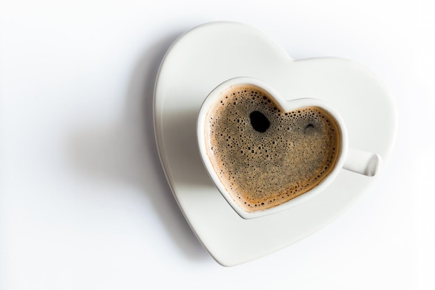 Una taza de café negro en forma de corazón en el amor blanco