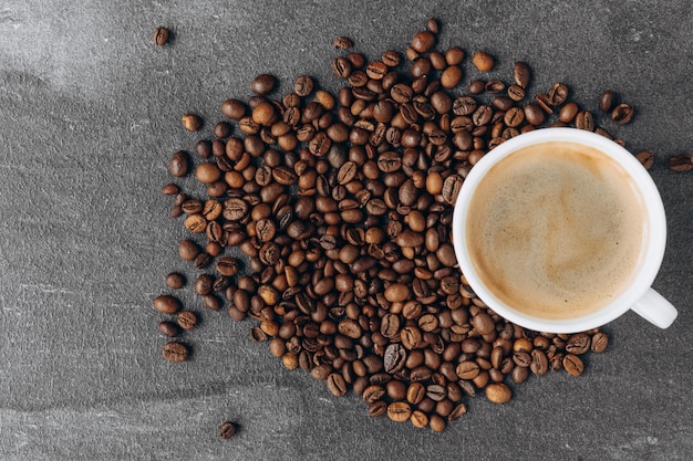 Taza de café negro con frijoles en la mesa de madera