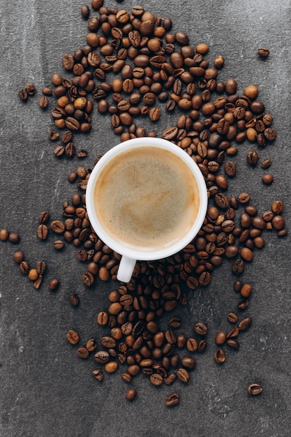 Taza de café negro con frijoles en la mesa de madera