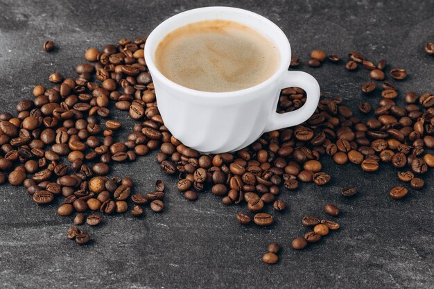 Taza de café negro con frijoles en la mesa de madera