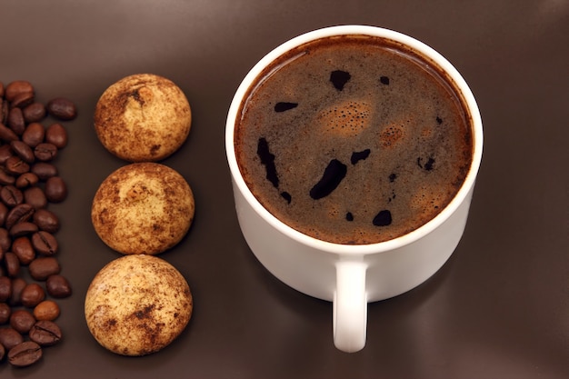 Taza de café negro con galletas y frijoles en una placa oscura