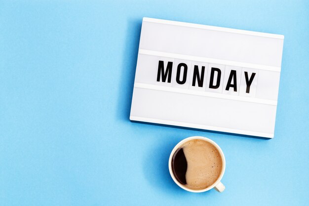 Taza de café negro y lightbox con word monday.