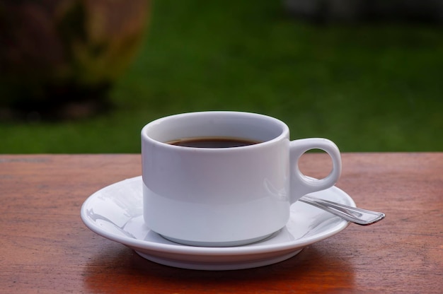 Una taza de café negro por la mañana en la mesa de madera