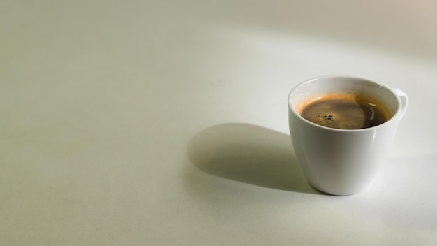 taza de café negro en la mesa blanca