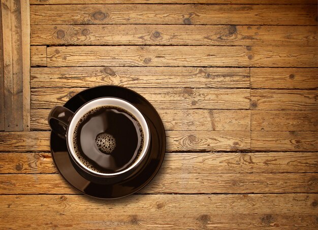 Una taza de café negro en una mesa de madera