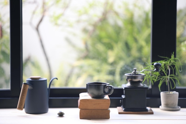 Taza de café negro y molinillo y olla de goteo en la mesa de madera