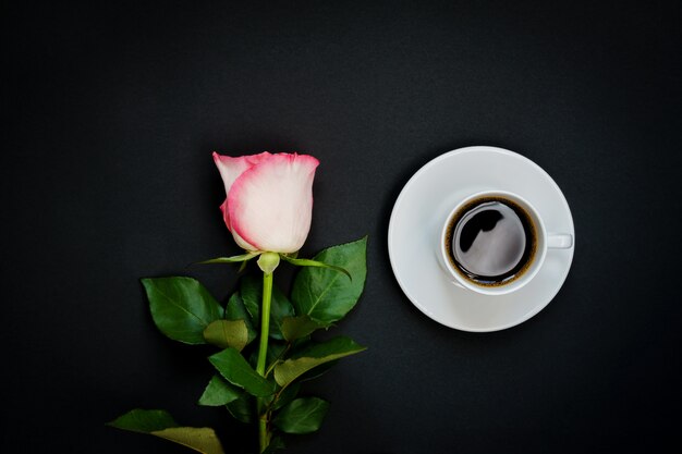 Taza de café negro y rosa rosa en negro, vista superior, espacio de copia.