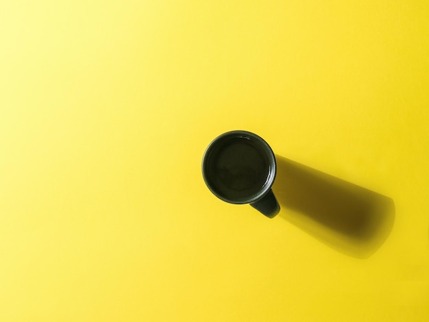 Una taza de café negro sobre un fondo amarillo brillante Minimalismo