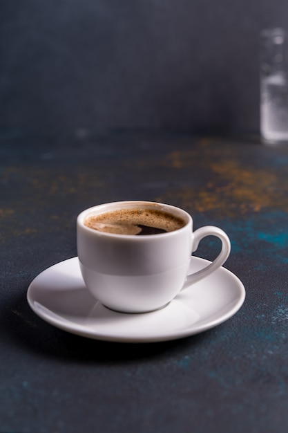 Taza de café negro sobre fondo azul mesa