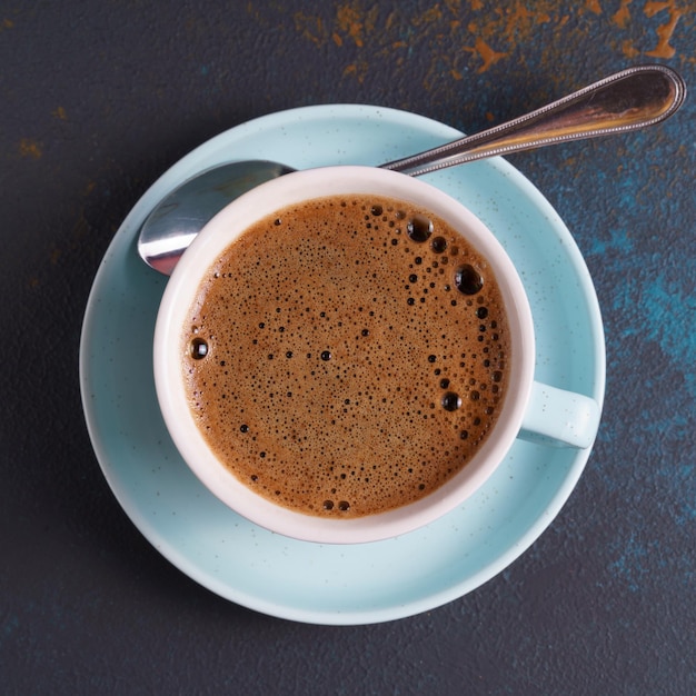 Una taza de café negro en una vista superior de fondo azul retro