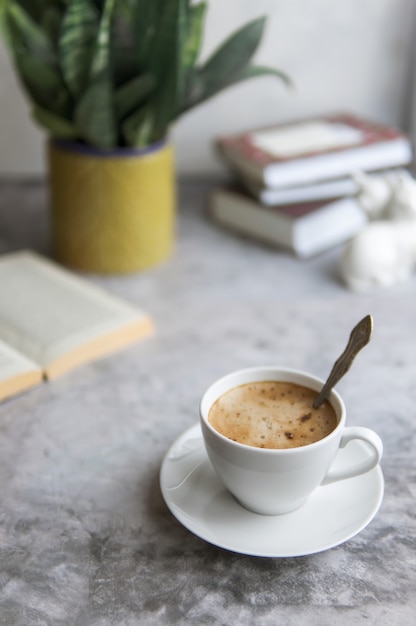 Taza de café o capuchino y libro sobre mesa gris de hormigón