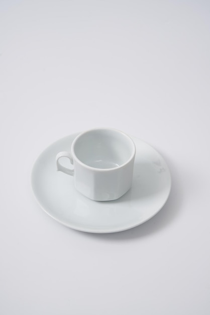 Taza de café o té de cerámica blanca y su plato sobre un fondo blanco