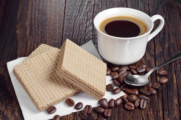 Taza de café y obleas con chocolate sobre mesa de madera rústica