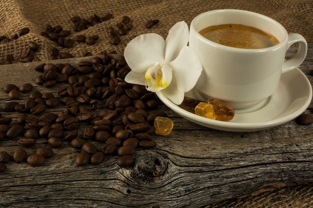 Taza de café y orquídea blanca en el fondo de madera