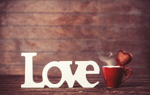Taza de café y la palabra amor en la mesa de madera