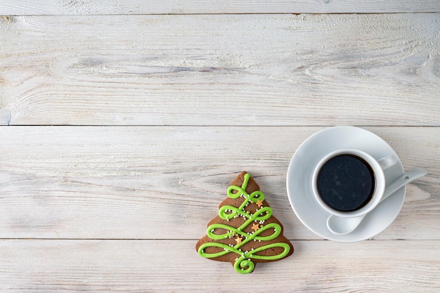 Taza de café y pan de jengibre sobre fondo blanco de madera, espacio de copia el enfoque selectivo