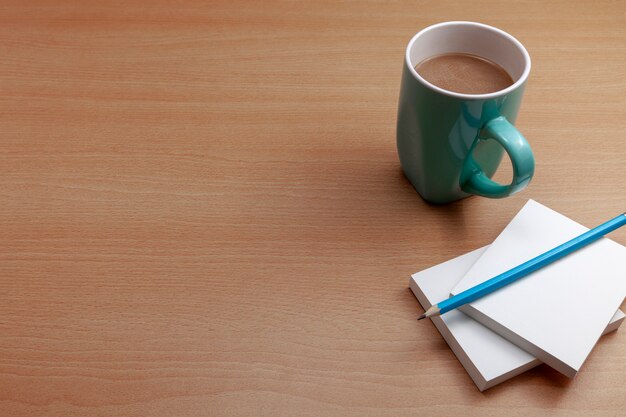 Taza de café con papel blanco y lápiz en la mesa de negocios