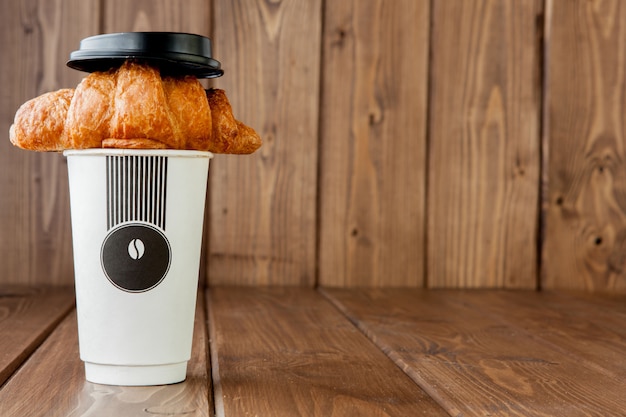 Taza de café de papel y croissant