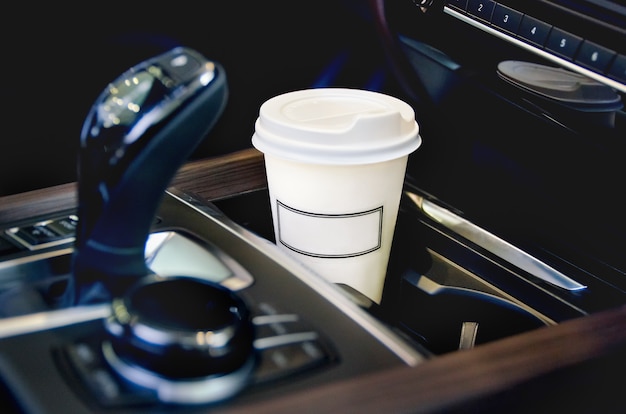 Una taza de café de papel dentro del portavasos del automóvil.