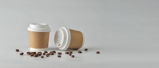 Taza de café de papel y granos de café en el fondo blanco.