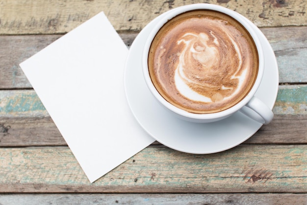 Taza de café y papel gunge sobre fondo de mesa de madera vieja al aire libre