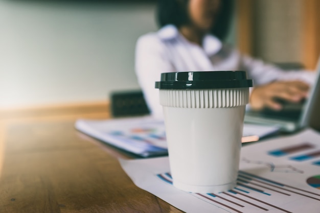 Una taza de café en el papel de informe con el fondo de la empresaria.