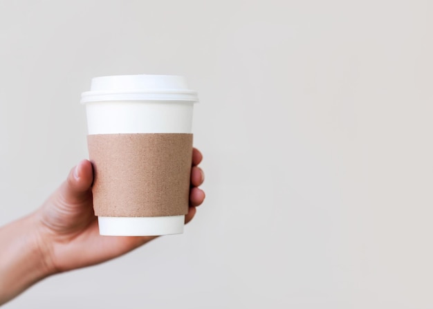 Taza de café de papel para llevar en la mano.