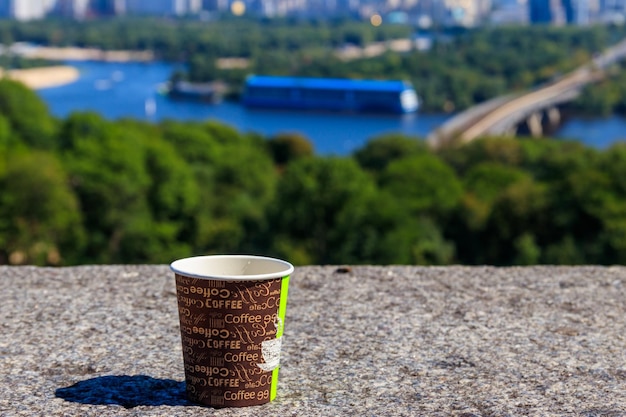 Taza de café de papel en un parapeto de piedra con vistas al paisaje urbano de Kiev Ucrania