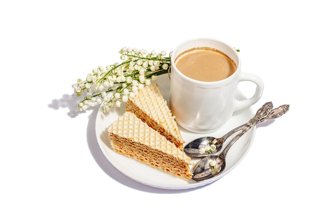 Taza de café y pastel de gofres aislado sobre un fondo blanco Postre dulce con ramo de lirios del valle