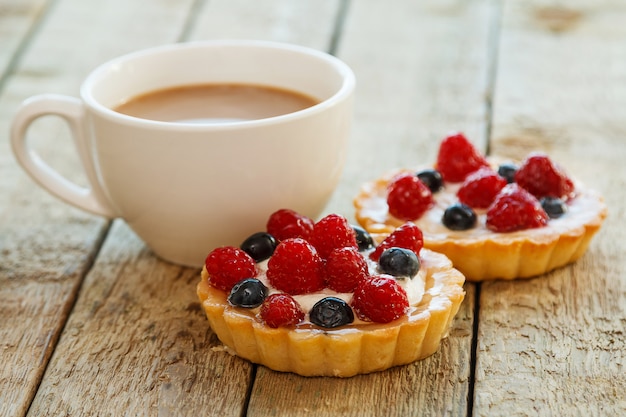 Taza de café y pasteles dulces con frutas del bosque