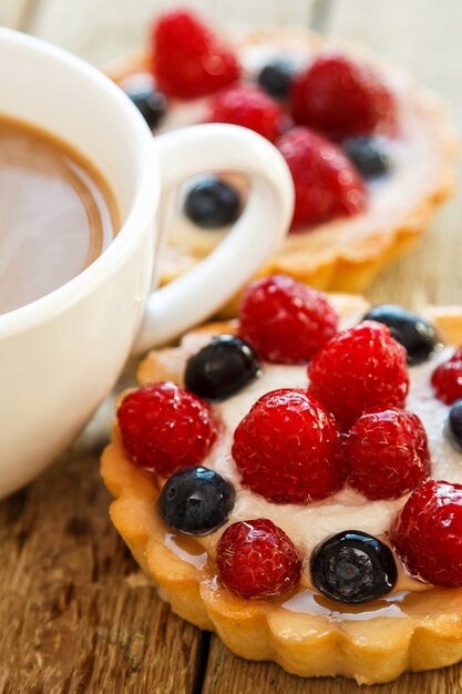 Taza de café y pasteles dulces con frutas del bosque