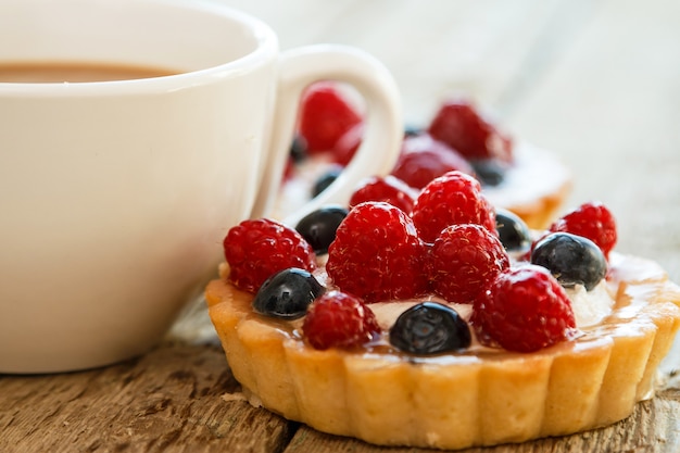 Taza de café y pasteles dulces con frutas del bosque