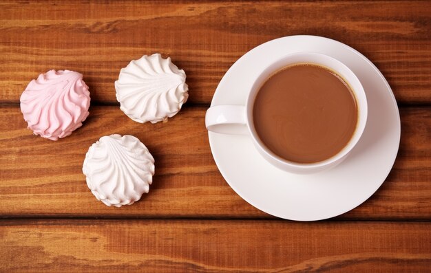 Taza de café y pasteles sobre fondo de madera.