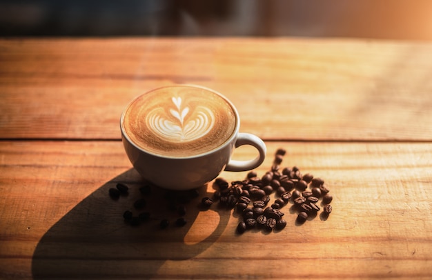 Una taza de café con patrón de corazón en una taza blanca sobre fondo de mesa de madera