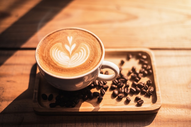 Una taza de café con patrón de corazón en una taza blanca sobre fondo de mesa de madera