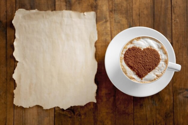 Taza de café con patrón creativo y papel sobre mesa de madera