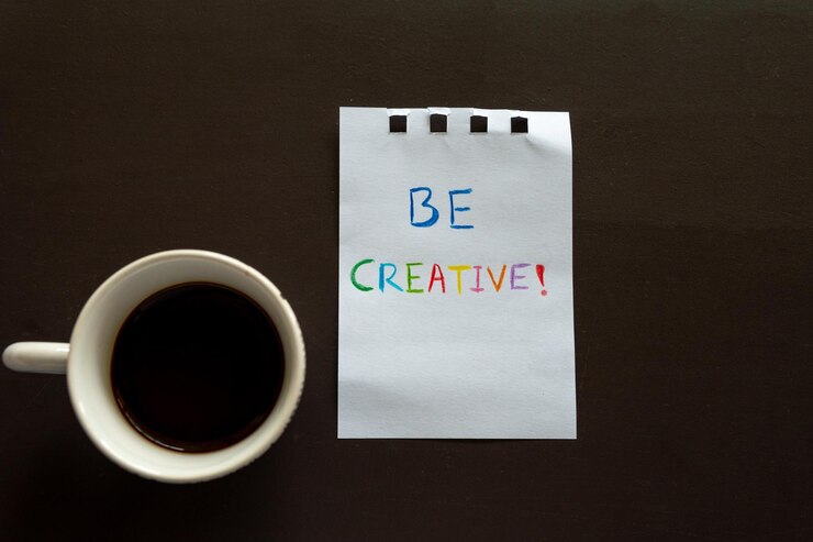 Una taza de café y un pedazo de papel con las palabras ser creativo