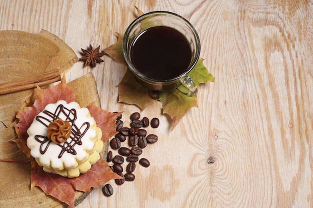 Taza de café, pequeño pastel redondo y hojas de otoño sobre fondo de madera vieja