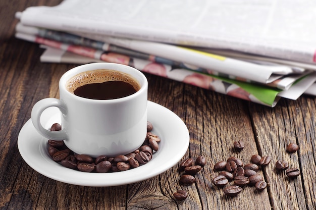 Taza de café y periódico en la mesa de madera antigua