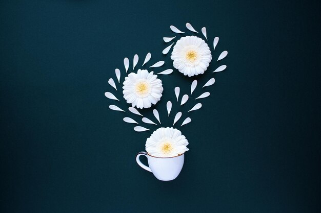 Taza de café con pétalos de flores de gerbera flatlay