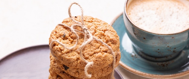 Taza de café, pila de galletas de avena sobre fondo de madera blanco Panadería casera bandera Gorisontal