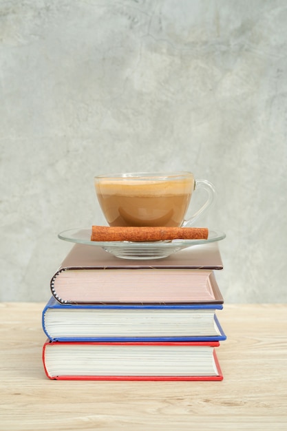 Una taza de café y una pila de un libro en una tabla de madera.