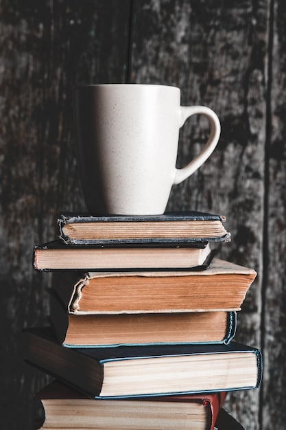 Una taza de café en la pila de libros sobre fondo gris. educación, estudio, aficiones, leer