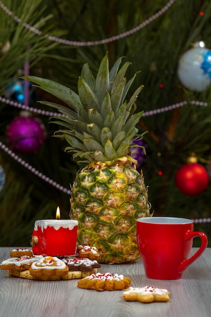 Taza de café con piña y un abeto con adornos navideños en el fondo