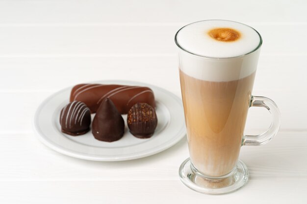 Taza de café y platillo con dulces de chocolate en la mesa de madera