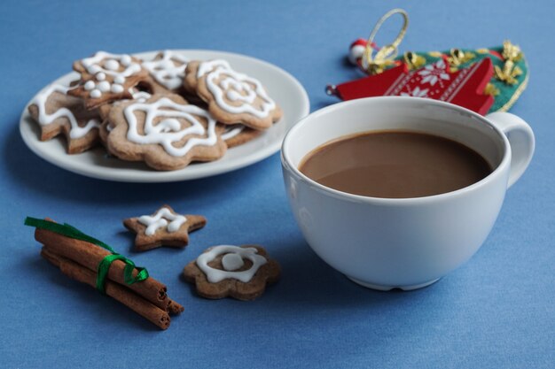 Una taza de café y un plato de galletas de jengibre navideñas con glaseado de azúcar blanco