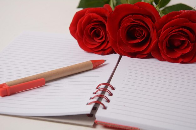 Taza de café, pluma de cuaderno y flores color de rosa Pausa para el café por la mañana