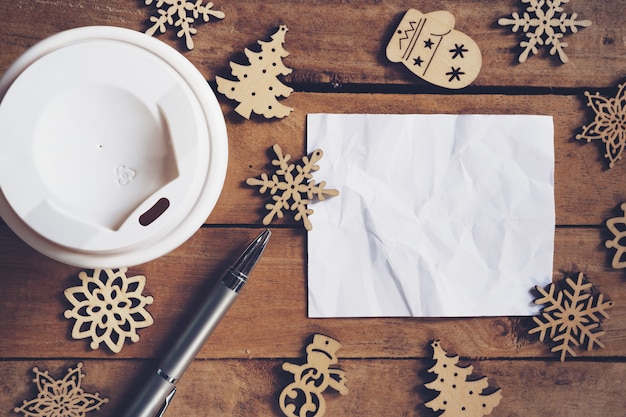 taza de café y pluma, papel vacío sobre madera con decoración de Navidad para el concepto de año nuevo.